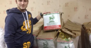 Чоловік тримає коробку гуманітарної допомоги Угорщини для України серед посилок